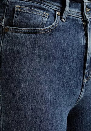 Zbliżenie na ciemnoniebieskie dżinsy, ukazujące przednią kieszeń, kieszeń na monety, szlufkę do paska oraz detal zamka.