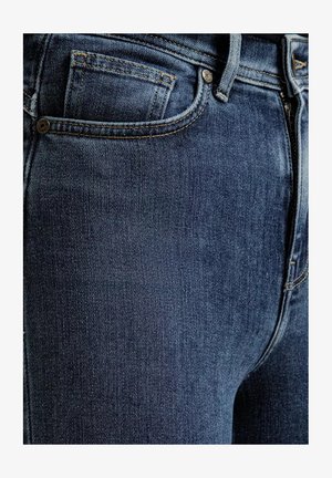 Zbliżenie na ciemnoniebieskie dżinsy, ukazujące przednią kieszeń, kieszeń na monety, szlufkę do paska oraz detal zamka.