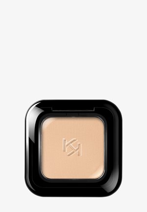 Poudre compacte pour le visage beige de forme carrée avec une surface texturée et un logo embossé, logée dans un étui carré noir brillant.