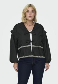 Czarna krótka kurtka z dekoltem w serek, z kokardkami z przodu oraz białą koronkową lamówką u dołu. Długie, bufiaste rękawy dopełniają całość.