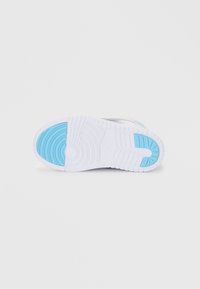 Sneaker zole ar baltu gumijas pamatni un zilu akcentu uz papēža, strukturētiem zīmējumiem un apļveida rakstu saķerei.