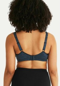 Marinblå bh med spetsbak, justerbara axelband och hak-och-öga stängning. Funktioner med texturerad tyg och subtila blommönsterdetaljer.