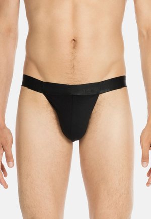 Schwarze Strings aus weichem Stoff mit einem glatten Bund, der mit eingeprägtem Branding versehen ist. Entworfen für eine enge Passform am Körper.