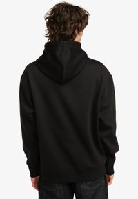 Felpa nera con cappuccio, dalla texture liscia, vestibilità oversized, polsini e orlo a coste, e senza loghi o motivi visibili sul retro.
