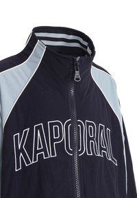 Veste coupe-vent navy avec le logo "KAPORAL". Dotée d'accents bleu clair, d'un col haut et d'une fermeture éclair. Tissu lisse avec un design sportif.