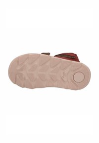 Roter Schuh mit einer strukturierten Gummisohle, die ein Zickzackmuster für besseren Halt aufweist. Ein Klettverschluss ist oben sichtbar.