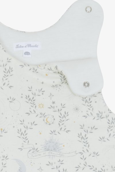 Υπνόσακος από κρεμ ύφασμα με ασημένια και χρυσά ουράνια σχέδια, ελαφρύ υλικό, κούμπωμα με κουμπιά και στρογγυλή λαιμόκοψη. Περιλαμβάνεται ετικέτα μάρκας.