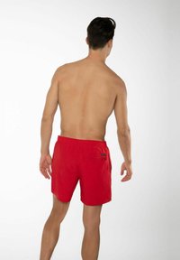 Pantaloni da bagno rossi con cintura elastica e tasca con zip sul retro. Realizzati in tessuto leggero, progettati per comfort e libertà di movimento.