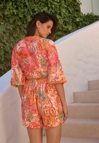 Ensemble deux pièces composé d'un top court et d'un short, fabriqué dans un tissu léger avec un motif paisley vibrant en rose, orange et teal.