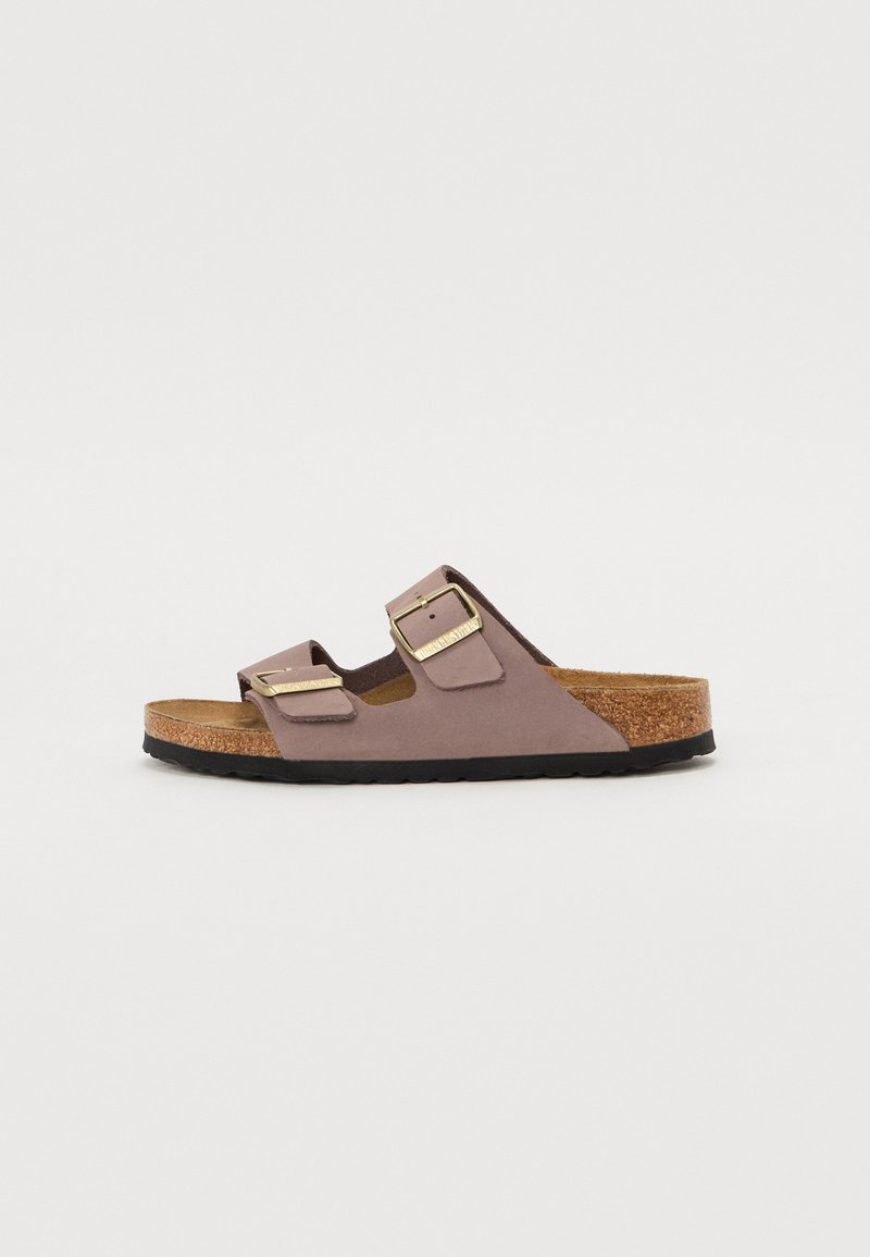 Sandal con suola in sughero marrone, dotato di due ampie cinghie in un morbido materiale malva, con fibbie in tonalità dorata per una vestibilità regolabile. Suola in gomma.