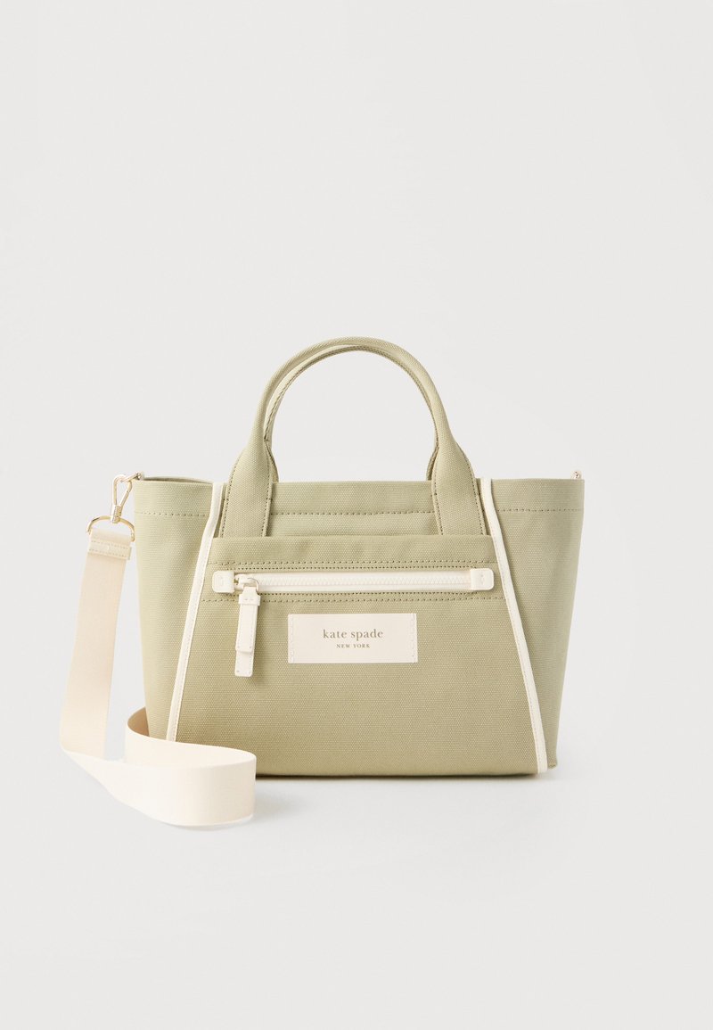 Μικρή ελαφριά τσάντα καμβά σε ελιά πράσινο χρώμα με λευκό φερμουάρ σε θήκη, διπλές λαβές και αφαιρούμενο φαρδύ λευκό ιμάντα ώμου.