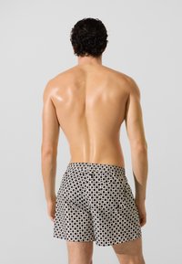 Mustvalged ujumispüksid mustriga, millel on elastne vöökoht ja püksisääred kuni reie keskosa, geoemetrilise ruudustiku kujundusega. Sile tekstuur.