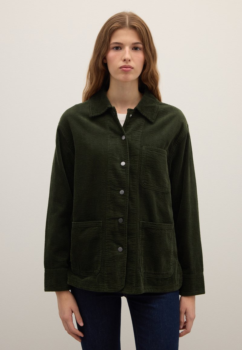 Corduroy jacket in dark green with a button-up front, collar, and two front pockets. Features a textured fabric with vertical ribbing.