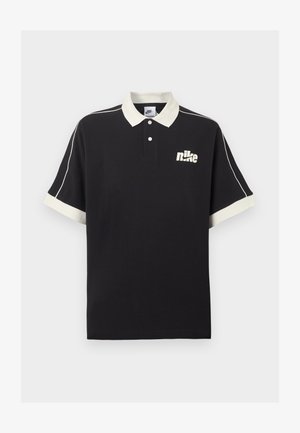 Polo nera a maniche corte con colletto e polsini bianchi, piping bianco sulle maniche e logo Nike bianco sul petto a sinistra.
