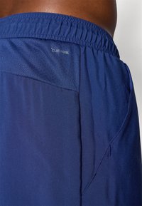 Pantalones cortos deportivos en color marino con un tejido ligero y transpirable. Presentan una cinturilla elástica y un panel de malla para ventilación.