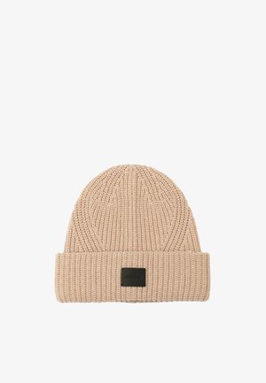 Gorro de punto en color beige claro con textura acanalada y puño doblado. Presenta una etiqueta rectangular negra en la parte frontal.