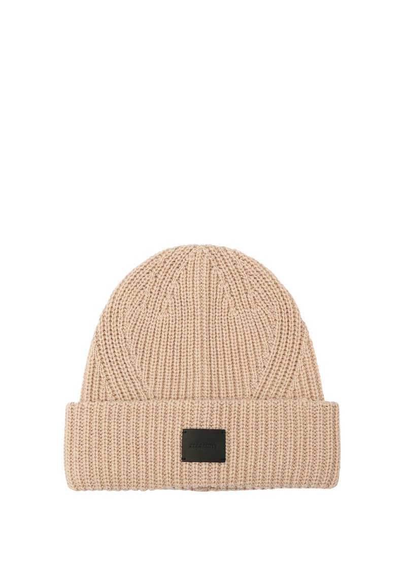 Gorro de punto en color beige claro con textura acanalada y puño doblado. Presenta una etiqueta rectangular negra en la parte frontal.