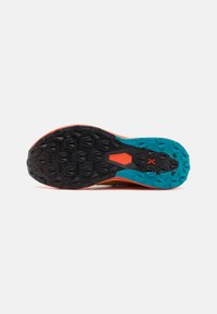 Semelle de chaussure de trail avec une base en caoutchouc noir, des accents turquoise et une bordure orange. Texture remarquable avec des motifs de traction prononcés.