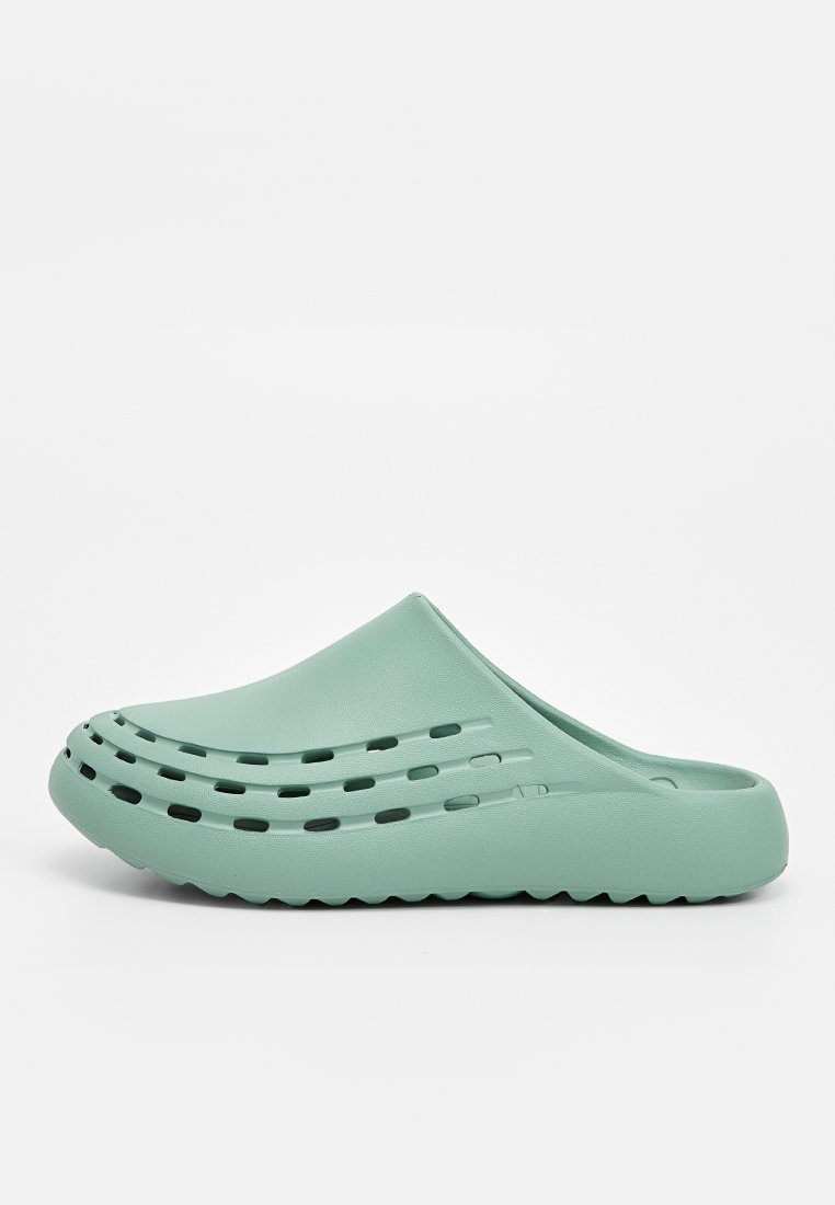 Sabot léger vert en matériau flexible, comportant des trous de ventilation découpés et un design texturé sur la tige et la semelle.