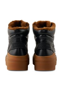 Ein Paar schwarze Lederstiefel mit braunem Pelzfutter und dicken braunen Gummisohlen, von hinten betrachtet, mit "BOGNER"-Markierung.