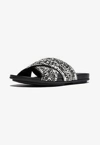 Zwart-witte schuursandalen met een geweven bandontwerp. Heeft een platte zool en open teen. Gemaakt van een gestructureerd materiaal voor extra grip en comfort.