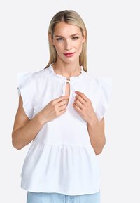 White blouse with ruffled sleeves, keyhole neckline, and peplum hem. Made of lightweight fabric with a smooth texture.
