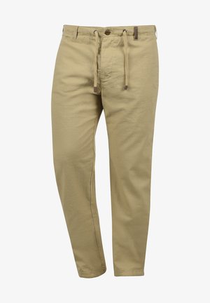 Pantalon en lin beige avec une coupe décontractée, ceinture élastique à cordon, et un bouton marron unique à l'avant. Texture lisse partout.