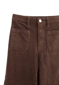 Brune fløjlsbukser med en vertikal ribstruktur, der har en knaplukning og to baglommer.