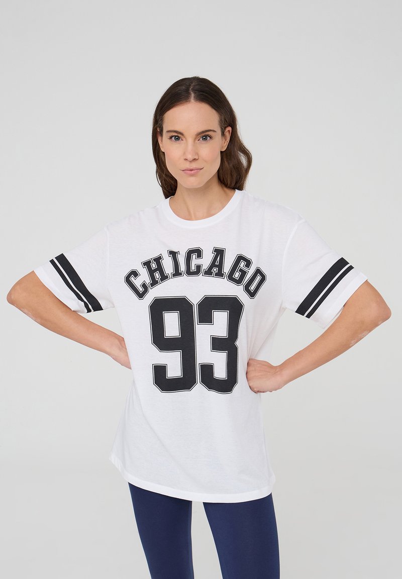T-shirt bianco con la scritta "CHICAGO" e il numero "93" in nero, con strisce nere sulle maniche e una vestibilità rilassata. Tessuto di cotone liscio.