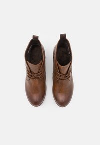 Braune Leder-Stiefeletten mit glatter Textur, rundem Zehenbereich und dekorativen Nähten; verfügen über eine Schlaufe am Absatz für ein einfaches Anziehen.