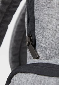 Γκρι σακίδιο fabric με λείο φερμουάρ και μαύρη λαβή, που τονίζει την υφή της επιφάνειας του υλικού και τον αντίθετο περίγυρο.