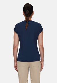 Camiseta de manga corta azul marino con puños enrollados, que presenta un sutil logo de la marca en la parte posterior. Textura suave, diseño ajustado.