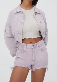 Jasnofioletowa denimowa kurtka i szorty, o skróconym kroju, z postrzępionymi krawędziami oraz jasnoszary prążkowany top z falbankowym obrzeżem.