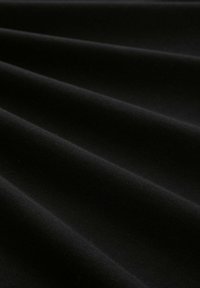 Tela negra con una textura suave, que presenta pliegues profundos. El material parece resistente y tejido, creando una superficie rica y contrastante.