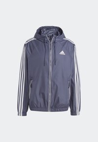 Veste à capuche Adidas bleu marine avec trois bandes blanches sur les manches, fermeture éclair frontale, poignets élastiques et poches avant zippées.