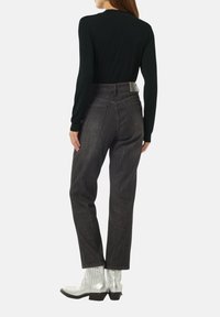 Pantaloni in denim grigio scuro con vita alta, cinque tasche e una sottile trama. Abbinati a un top aderente nero a maniche lunghe e stivali alla caviglia argentati.