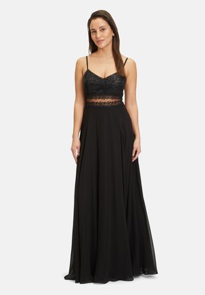 Abito da sera nero con un corpetto fitted in paillettes e una gonna fluida. Spalline a spaghetti e dettagli in pizzo trasparente in vita.