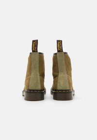 Stivaletti in suede marrone e verde fino alla caviglia con punta rotonda, suole in gomma nere e cuciture gialle. Presentano linguette sul retro.