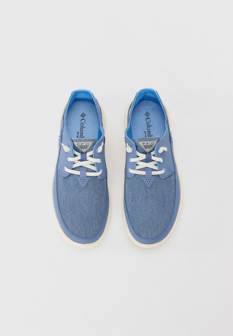 Niebieskie płócienne buty z jasnoniebieskimi akcentami i białymi sznurówkami. Posiadają perforowany wzór na języku, metkę z logo oraz białą podeszwę.