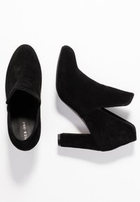 Botines de ante negros con tacón, de diseño elegante, punta afilada y detalle recortado en los lados. El tacón ligeramente grueso aporta estabilidad.