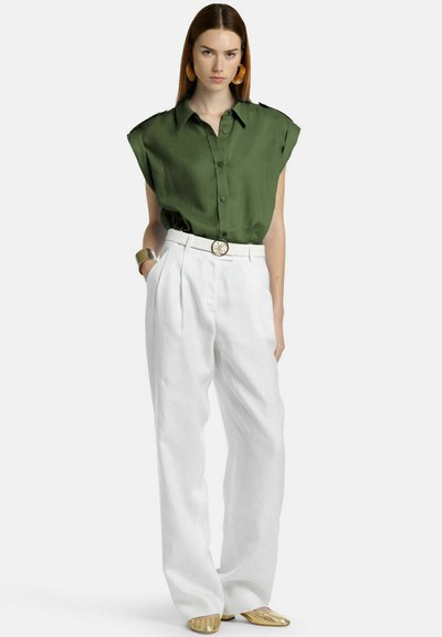 Green short-sleeve blouse with a collar, paired with white high-waisted linen trousers. Includes a gold belt buckle and metallic shoes.