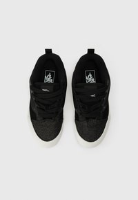 Mustat tennarit, joissa on kimalteleva musta varvasosa, nauhoitustyyli ja valkoinen kumiulkopohja. Pehmeä kangas päällinen, jossa on logoyksityiskohta sisäpohjalla.