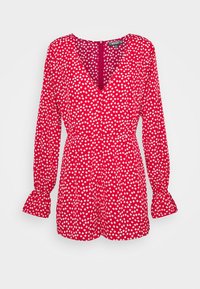 Combinaison rouge à pois blancs avec manches longues, col en V et fermeture par boutons. Dotée de manches bouffantes aux poignets et d'une taille cintrée.