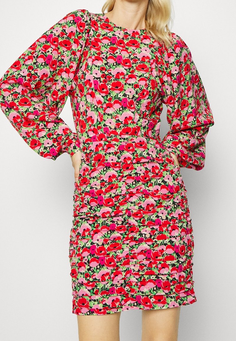 Robe fleurie ajustée avec de longues manches bouffantes aux nuances rouge, rose et vert, comportant une jupe texturée froncée et un col rond.
