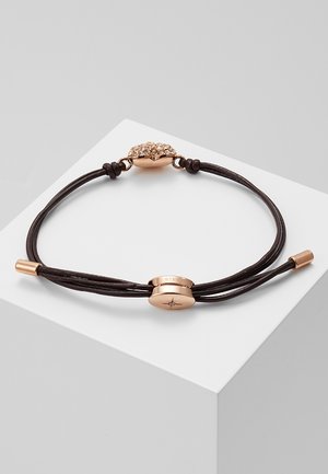 Bracelet en cuir noir avec fermoir magnétique en or rose et ornement central en or rose gravé d'une étoile, présenté sur une surface blanche.