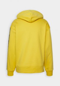 Yellow hoodie with a hood, made of soft material. Features ribbed cuffs and hem. Back view shows no additional design elements or patterns.