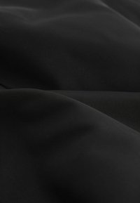 Tissu noir au toucher lisse avec une légère brillance. Présente des motifs de nervures subtils et des plis, indiquant douceur et flexibilité.