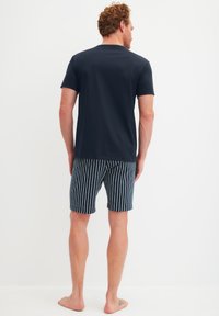 Marineblauw t-shirt van een katoenmix, gecombineerd met blauw-witte verticaal gestreepte zwembroek, dat een ontspannen pasvorm en een casual ontwerp laat zien.