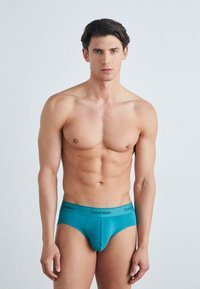 Aqua-blaue Baumwollunterhose mit schwarzem "Calvin Klein" Bund, figurschmeichelndes Design, das eine glatte Textur und einen minimalistischen Stil zeigt.