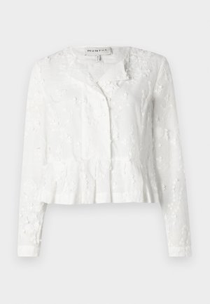 Hvit bluse med lange ermer, blomstermønster, peplum-skjørt og knappåpning foran. Laget av lett materiale med en teksturert overflate.